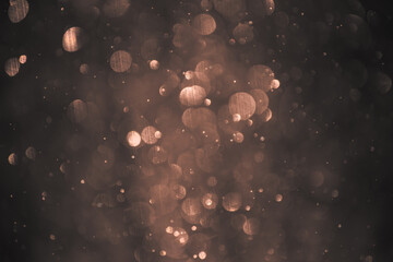 Blurred snowflakes in golden light. Colorful glowing bokeh abstract background.