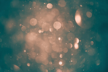 Blurred snowflakes in golden light at sunset. Colorful glowing bokeh abstract background.