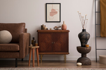 Interior design of cozy living room interior with mock up poster frame, brown sofa, stylish sideboard, vase with dried flowers, glass bottle, bowl with coconut, plaid, round pillows.  Home decor.
