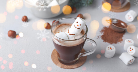 Snowman made of soft marshmallows in cup of hot chocolate on light background