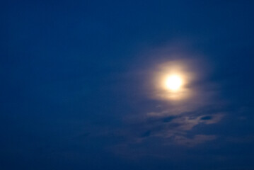 Fototapeta na wymiar A hazy moon glowing in a dark blue sky