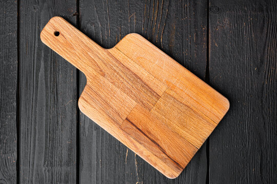 Wooden cutting board, on black wooden table background, top view flat lay , with copy space for text or your product