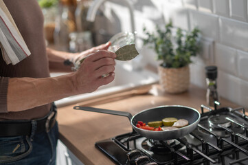 Man frying omlette in the kitchen and looking involved