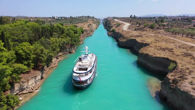Aerial drone video of yacht crossing famous narrow Corinthian gulf canal known as Isthmus from Saronic gulf to Corinthian gulf avoiding making full tour of Peloponnese, Greece
