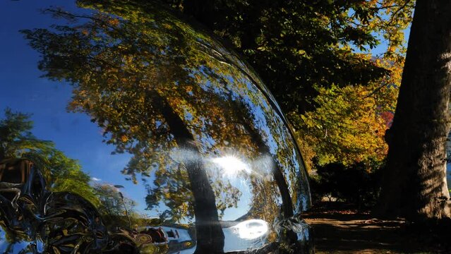 Metal Sphere with Tree Reflection in Autumn with Sunlight in Lugano, Ticino, Switzerland.