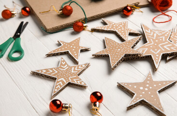 Cardboard stars with Christmas balls on white wooden background, closeup