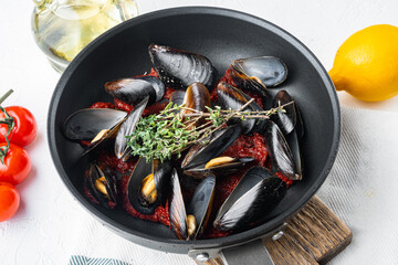 Delicious cooked seafood mussels with tomato sauce, on frying iron pan, on white background