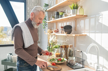 Gray-haired mature man cooking in the kitchen