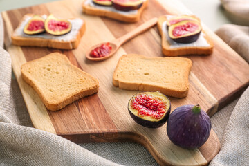 Fototapeta na wymiar Wooden board of tasty bruschettas with cream cheese and fresh figs on table, closeup