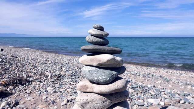 shingle beach (flat pebble) from shore of Lake Baikal and tourist pyramids