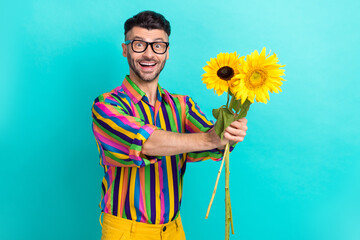 Photo of positive young person toothy smile hands hold bunch sunflowers give empty space isolated...