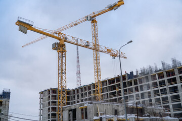 Steel reinforcement structure of rebars for concrete pouring at construction site. Tower crane and unfinished residential buildings. Housing construction, apartment block with formwork at winter