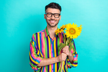 Photo of positive nice person beaming smile hands hold bunch sunflowers isolated on aquamarine...