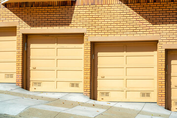 Orange brick building with row of garage doors yellow in late afternoon sun in the downtown neighborhood on apartment complex