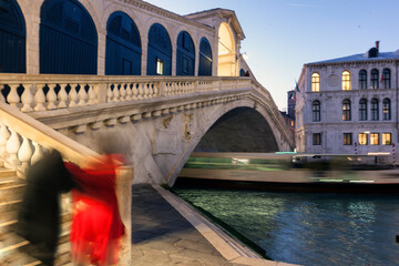 Venezia. Ponte di Rialto con persone e scia di vaporetto in transito sotto l'arco