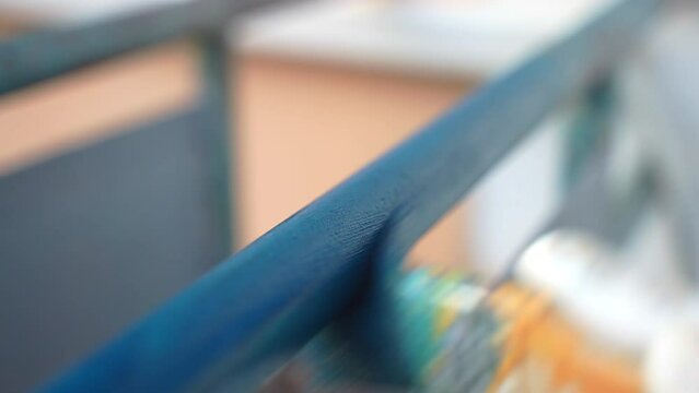 Close up shot of paintbrush covering iron pipe with blue colour, worker in gloves painting metal frame processed from rust and corrosion. Painting exterior metal constructions with bright colours