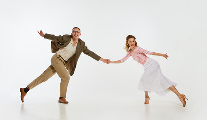 Two emotional dancers in vintage style clothes dancing swing dance, rock-and-roll or lindy hop isolated on white background. 1960s american fashion style and art.