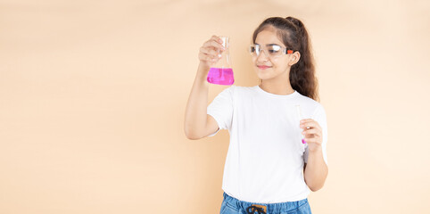 Young indian girl student doing science experiment holding colorful chemical flask isolated over...