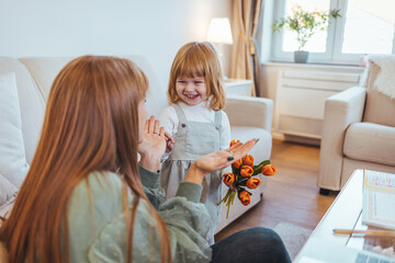 Happy mother's day. Child daughter congratulates moms and gives her a postcard and flowers tulips. Happy mother's day concept. Child daughter congratulates mom and gives her flowers tulips. 