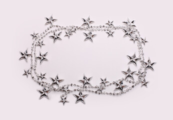 Silver star garland frame on light beige empty copy space background.