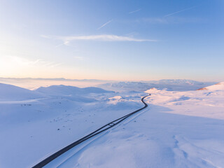 Aerial view of an empty road at winter time. Driving in forest after snowfall. 