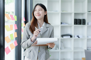 Portrait of a thoughtful Asian businesswoman looking at financial statements and making marketing plans at office