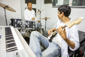 Music Students: Jamming Session. A guitarist and drummer rehearsing together in a music studio. From a series of related images.