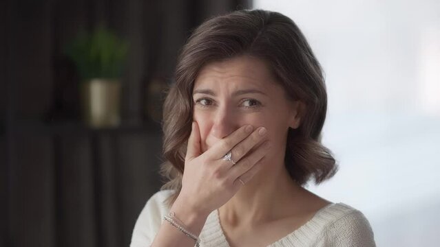 The young woman is embarrassed and ashamed, she repents and regrets because she realized that she made a stupid mistake. Portrait of an adult in a home environment. Female face close-up.