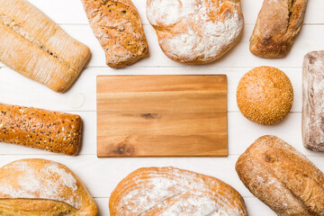 Minimalist wooden cutting board blank mockup on background of Types of homemade bread. Different...