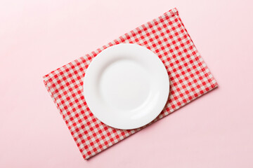 Top view on colored background empty round white plate on tablecloth for food. Empty dish on napkin with space for your design