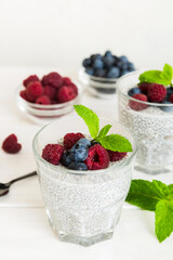 Healthy breakfast or morning with chia seeds vanilla pudding raspberry and blueberry berries on table background, vegetarian food, diet and health concept. Chia pudding with raspberry and blueberry