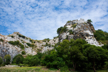 Fototapeta na wymiar View landscape range is a series of small limestone mountains in Tham Khao Ngu stone rock park with cloud blue sky for thai people and foreign travelers travel visit rest relax in Ratchaburi, Thailand