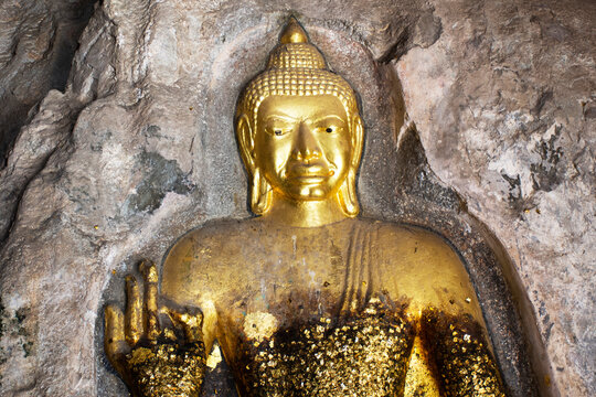 Carving stone and sculpture buddha image statue on cave wall of Tham Khao Ngu for thai people travel visit and respect praying blessing mystical at limestone mountain rock park in Ratchaburi, Thailand