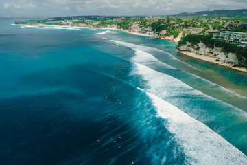 Aerial view of ocean with long waves and coastline on Impossibles beach in Bali