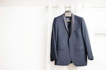 Fototapeta na wymiar Blue suit hanging. Wedding preparation fashion background. Gentelman formal wear.