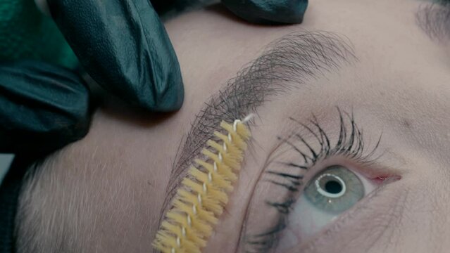 Eyebrow master shows the result of microblading work, moving the hairs of the eyebrow with a brush.