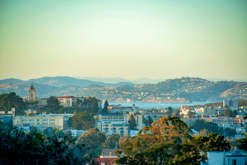 Sprawling buildings with background moutains and lakes with visible ocean and orange and blue gradient sunset sky in afternoon
