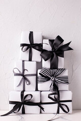 Black and white Christmas. Set of wrapped boxes with presents against white textured  wall. Scandinavian style. Place for text.
