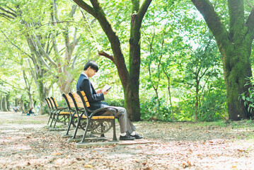 公園で本を読む男子高校生