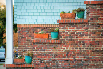 Outside brick exterior with decorative geen pots for plants and square adobe containes with white...