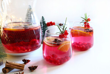 Punch all'arancia. Deliziosa bevanda con arancia e mirtilli rossi, ghiaccio e rosmarino su sfondo bianco. Natale e festività natalizie. Copia spazio.