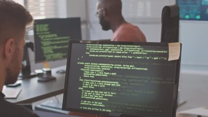 Diverse team of professional programmers typing program codes appearing on black screen of their computer monitors, working together in modern office - Powered by Adobe