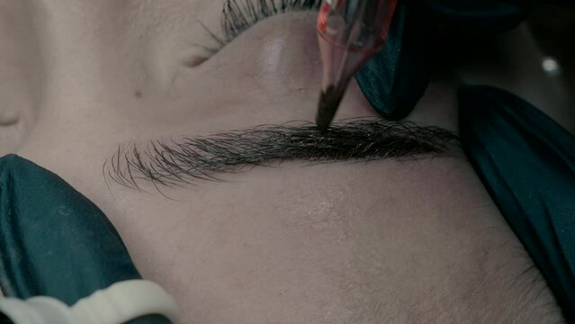 Master of microblading makes a pigment at the edge of the eyebrow. close up video 2