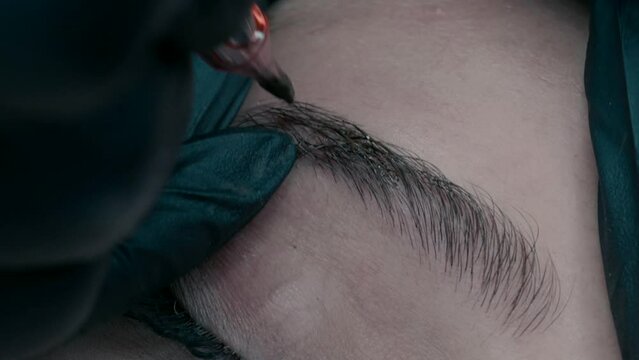 Master of microblading makes a pigment at the edge of the eyebrow. close up video 3