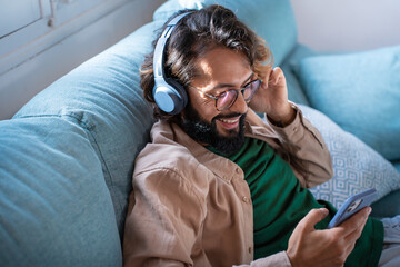 Smiling young man wearing headphones listen to mobile music playing in smartphone app, happy guy...