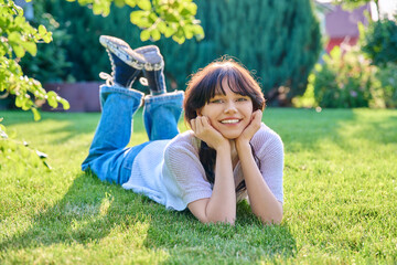 Outdoor portrait of young female 18 years old lying on grass