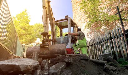 The excavator operator is getting ready to work hard. Construction of the entrance to the house, earthworks.