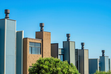 Row of chimneys with visible windows and front yard trees with blue and white sky in the historic districts of san francisco