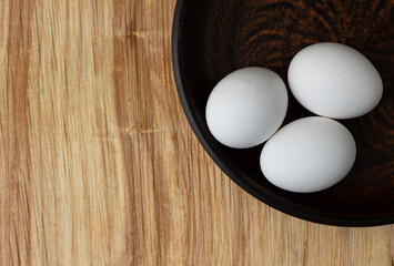 Eggs in a plate on a wooden background.