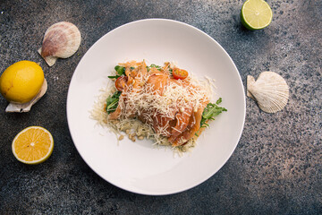 Salad with arugula, salmon, tomatoes, garnished with cheese and pine nuts